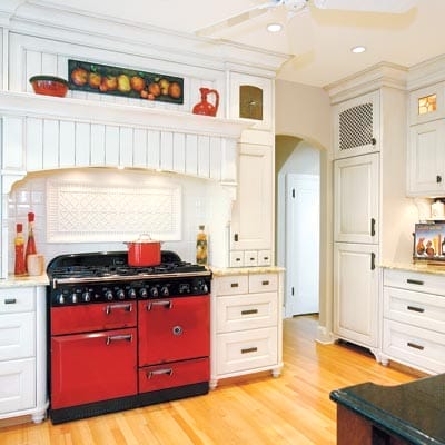 Kitchen with white cabinets and red oven.