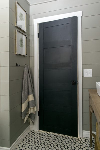Black paneled door made from 4-inch plywood strips.