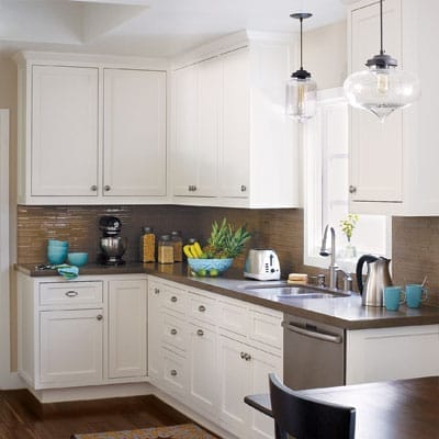 Corner of a kitchen with white cabinets and pendant lighting.