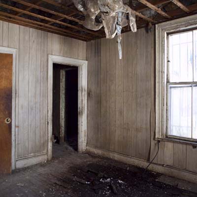 Bedroom with aging plaster walls requiring complete renovation.