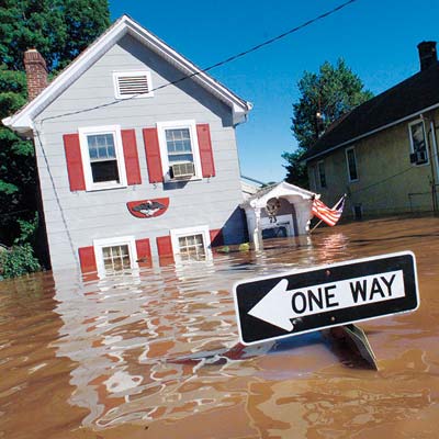 A house experiencing major flooding with a One Way sign in front of it