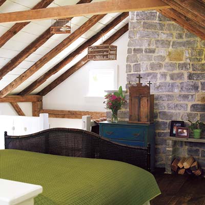 A bedroom with exposed stone and beams