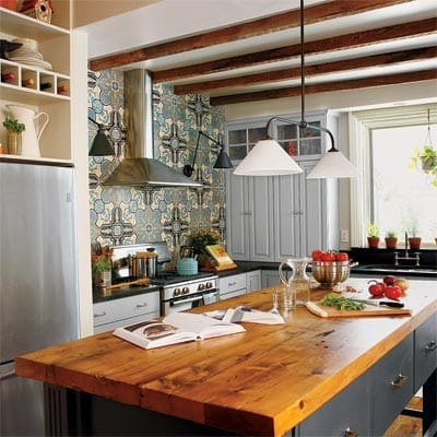 Kitchen with exposed beams, range hood, and cement tile backsplash.