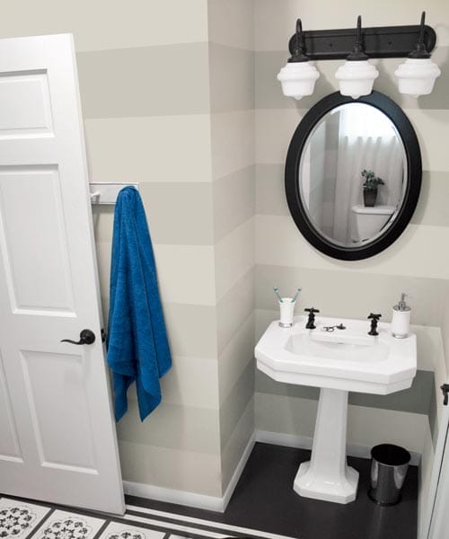 A small bathroom with horizontal stripes painted on the wall.