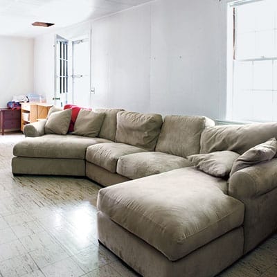 Basement before renovation with oversized sectional seating.