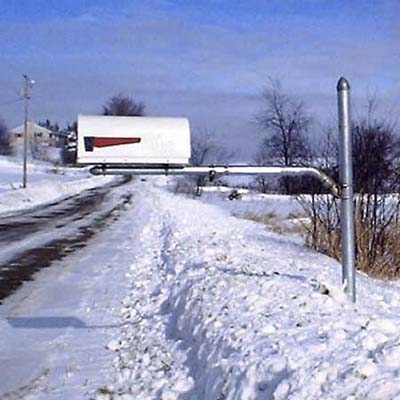 White swinging arm mailbox which allows the mailbox to extend further from the curb. 