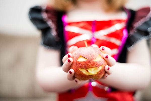 Image of an apple carved to look like a jack-o-lantern