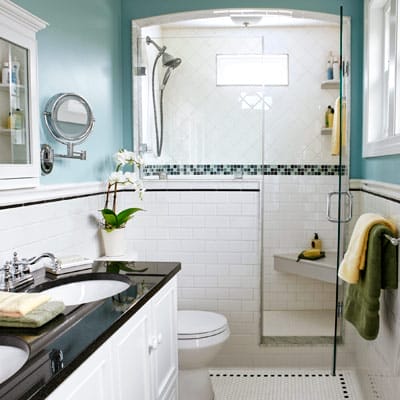 Narrow bathroom with white tile and frameless glass shower enclosure.