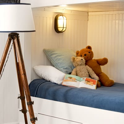 Individual bunk bed lighting with nautical sconces and personal switches for each bed.