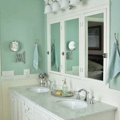 Bathroom with double vanities and seafoam-colored walls.