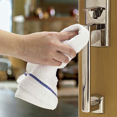 A person uses a cloth to clean a metallic entry set.