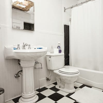 Dated bathroom before renovation with checkered vinyl flooring.