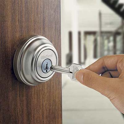 A person inserts a silver key into the lock of a silver entry set.