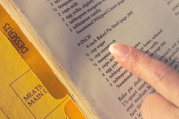 A hand pointing to a recipe for a pie