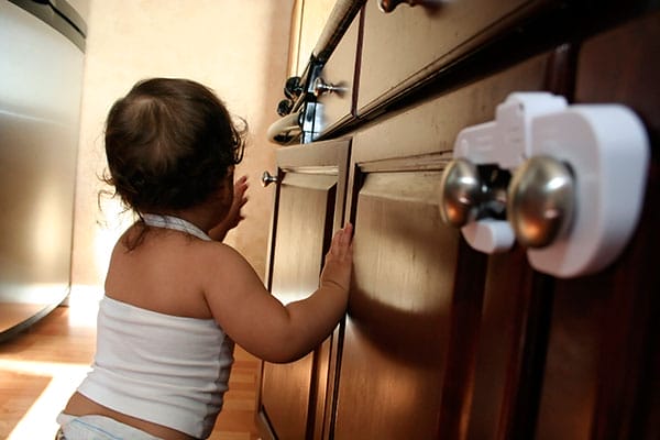 A baby reaching for a kitchen cabinet pull