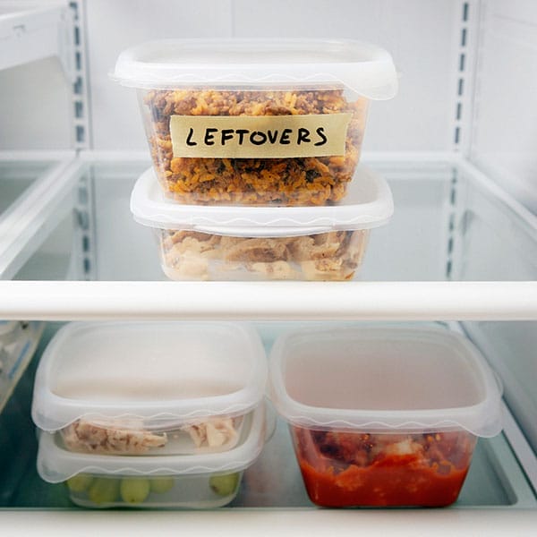 A container labeled "Leftovers" in a refrigerator