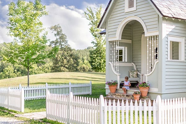 Storybook cottage with slate roof, inset porch, curved trim details, and built-in benches.