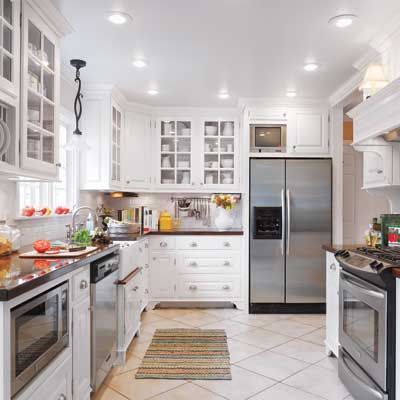 White kitchen with biscuit floor tiles and walnut countertop.