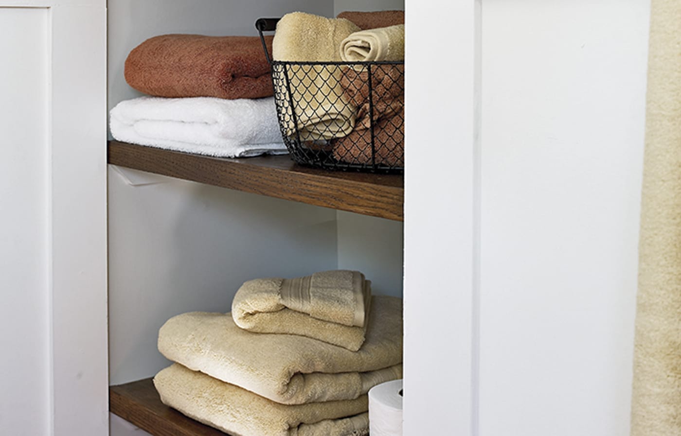 Open red oak shelving under eaves behind shower providing towel and toiletry storage.
