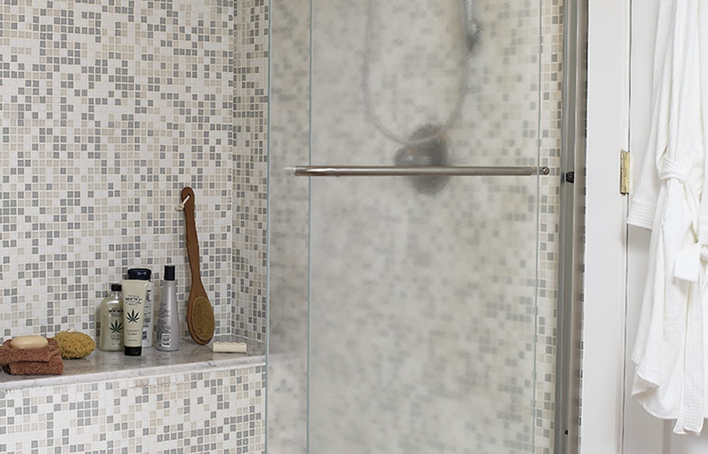 Mosaic tile shower with Carrara marble built-in seat.