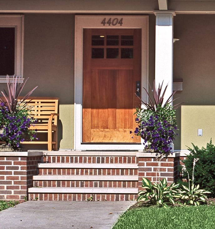 Bold black house numbers painted directly on light-colored siding above front door.