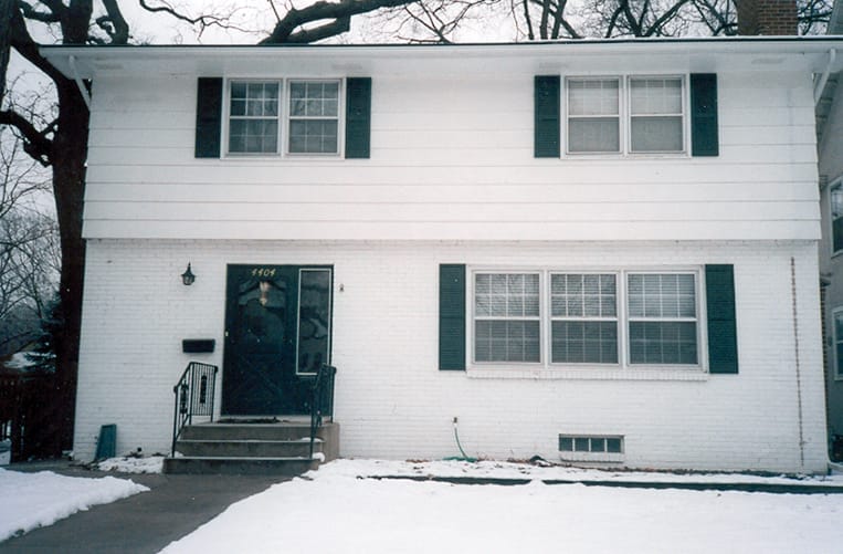 Boxy white 1960s ranch house with flat facade.