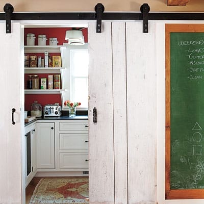 Pantry with period-appropriate open shelving and salvaged wood doors converted to barn-style sliders.