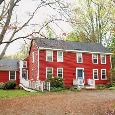 Original red-painted Georgian house before renovation showing weathered siding and dated entry configurations needing restoration work.