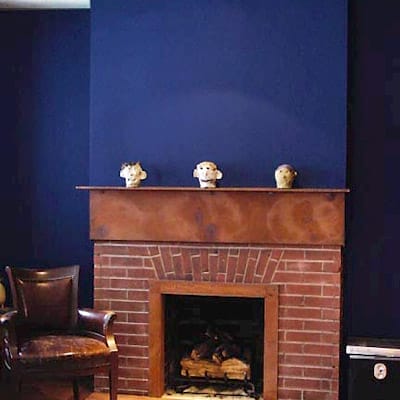 Lapis blue painted accent wall adding depth to exposed brick fireplace mantel.