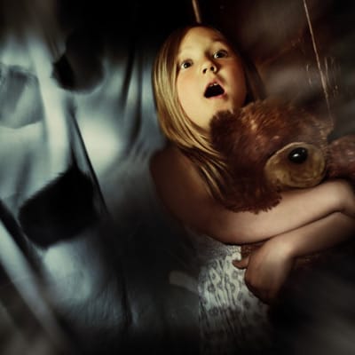A child clutching a teddy bear.