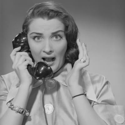 A woman holding a phone and screaming.