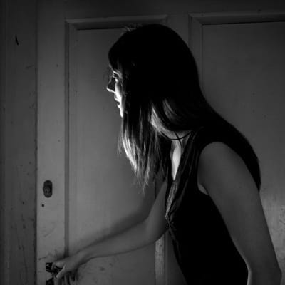 A woman opening a door in a haunted home.