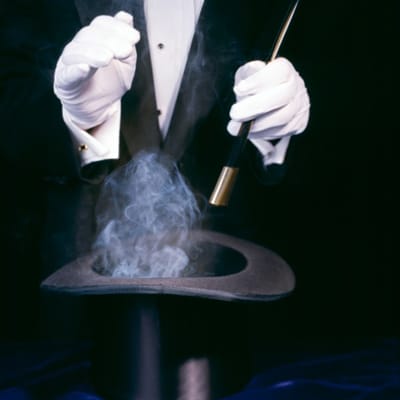 A magician holding a wand over a magic hat.
