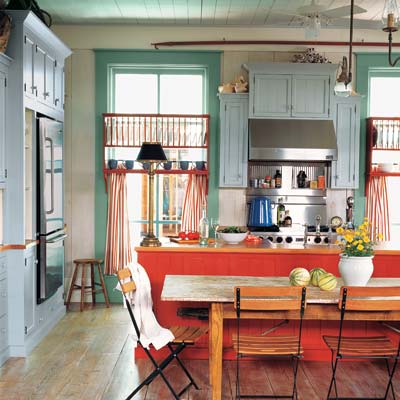 Caribbean-style kitchen with blue-green cabinets and red island with striped curtains.