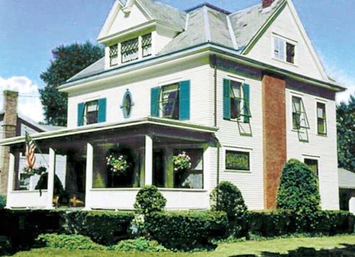 White Colonial Revival home with bright teal trim and shutters.