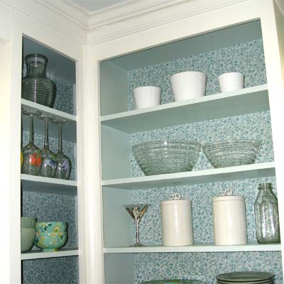 Open shelving with blue wallpapered backing.
