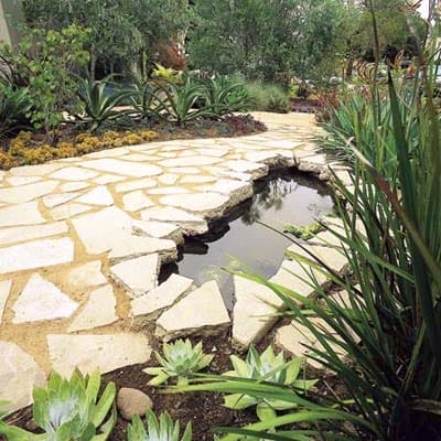 A pond in the middle of a stone pathway.