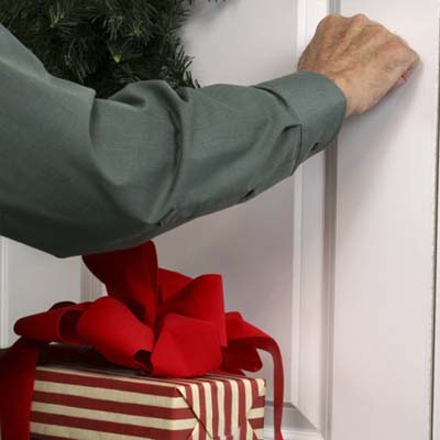 A person holding a gift and knocking on a door