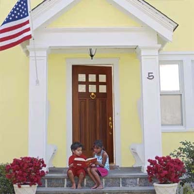 a freshly stained front door while kids sit on the front steps