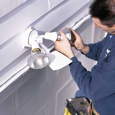 A man installing a garage floodlight