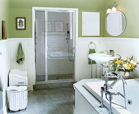 Green bathroom with white wainscoting, pedestal sink, and chrome fixtures.