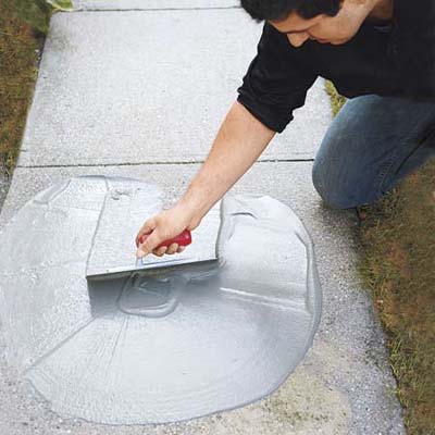 A man fixing a concrete walkway