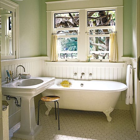 Bathroom with claw-foot tub, pedestal sink, beadboard walls, and garden view window.