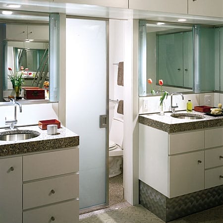 Clean modern bathroom with white cabinetry, stone countertops, floating vanities, and separate water closet.