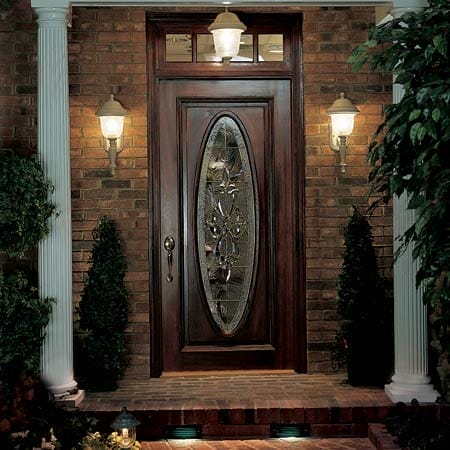 A front door being lit by two wall mount lanterns and a hanging light above.