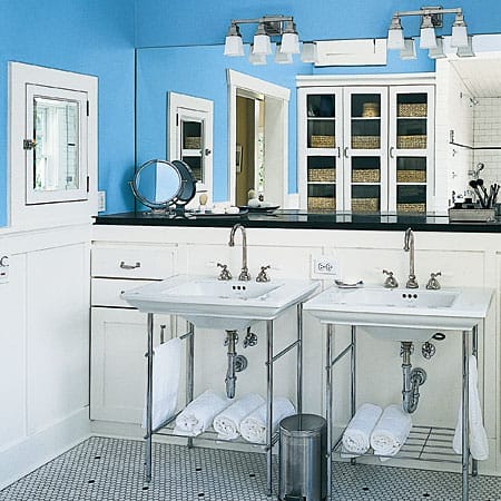 Bathroom with blue walls, wainscoting, exposed chrome plumbing, and black granite countertops.