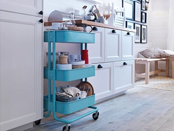 Three-level teal rolling cart with home essentials.