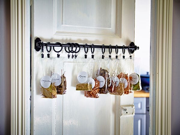 Bags of spices hanging from a door-mounted spice rod.