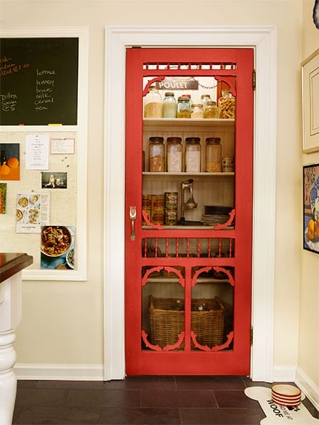 Screen pantry door painted red leading to organized pantry.