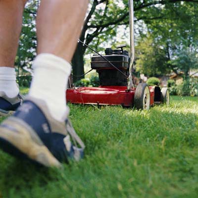 Close-up on shoes of person pushing a lawn mower.